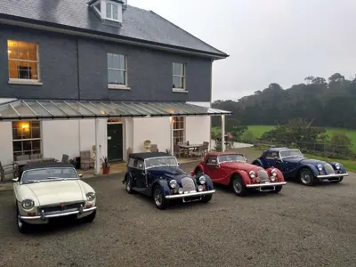 four old cars parked in front of a house at The Vean in Mevagissey