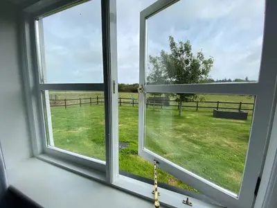 an open window with a view of a field at Seahorse Cottage in Helston