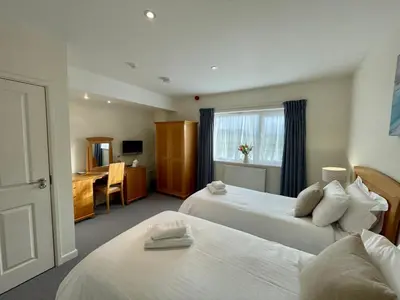a hotel room with two beds and a desk at Cosy room with golf & the beach on your doorstep! in Mawgan Porth