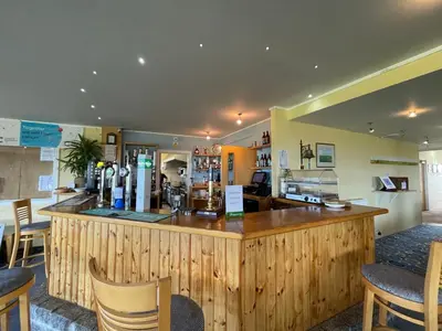 a restaurant with a large wooden counter and chairs at Cosy room with golf & the beach on your doorstep! in Mawgan Porth