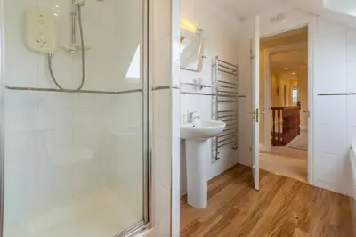 a white bathroom with a shower and a sink at April Cottage in Polzeath