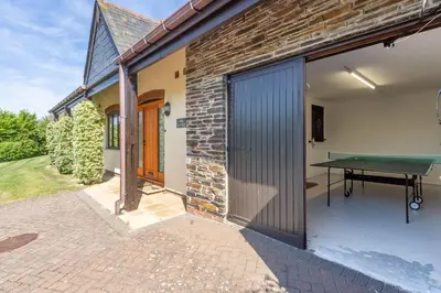 a brick house with a ping pong table on a patio at April Cottage in Polzeath