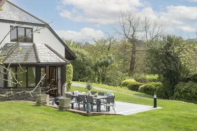 a patio with a table and chairs in front of a house at April Cottage in Polzeath