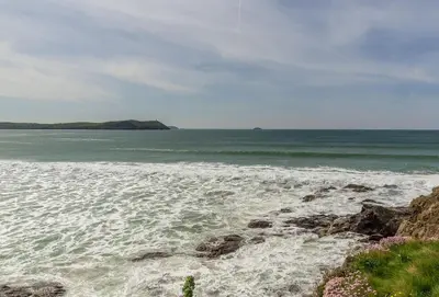 a beach with the ocean and some rocks at April Cottage in Polzeath