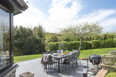 a patio with a table and chairs and a garden at April Cottage in Polzeath