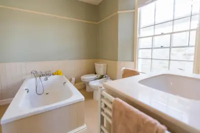 a bathroom with a tub and a toilet and a sink at Captain's House Falmouth in Falmouth