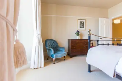 a bedroom with a bed and a chair and a dresser at Captain's House Falmouth in Falmouth