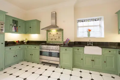 a green kitchen with a stove and a sink at Captain's House Falmouth in Falmouth