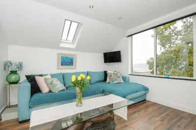 a living room with a blue couch and a window at Moon's Cottage in Fowey