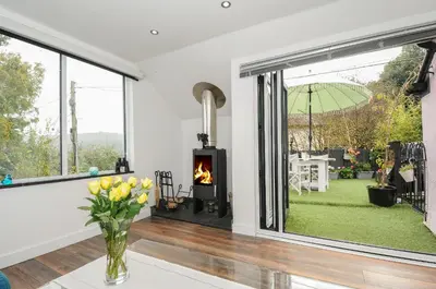 a living room with a fireplace and a window at Moon's Cottage in Fowey