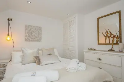 a white bedroom with a bed with towels on it at Moon's Cottage in Fowey