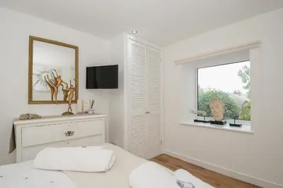 a white bedroom with a bed and a window at Moon's Cottage in Fowey
