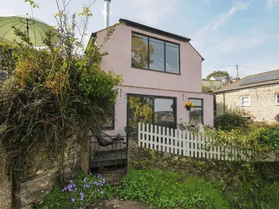 a pink house with a white picket fence at Moon's Cottage in Fowey