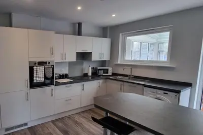 a kitchen with white cabinets and a table and a window at Cornish Village Getaway in Gwennap
