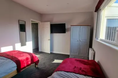 a bedroom with two beds and a tv in it at Cornish Village Getaway in Gwennap