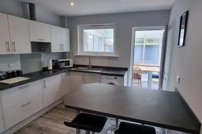 a kitchen with white cabinets and a black counter top at Cornish Village Getaway in Gwennap