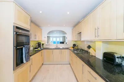 a large kitchen with wooden cabinets and black counter tops at Wavetop in St Ives