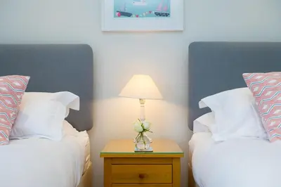 a bedroom with two beds and a lamp on a night stand at Wavetop in St Ives