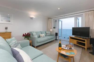 a living room with a blue couch and a television at Wavetop in St Ives