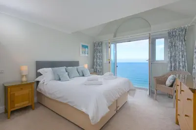 a bedroom with a large bed with a view of the ocean at Wavetop in St Ives
