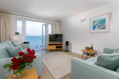 a living room with two blue couches and a television at Wavetop in St Ives