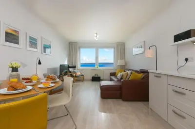 a kitchen and living room with a table and a couch at 28 Carrack Widden in St Ives