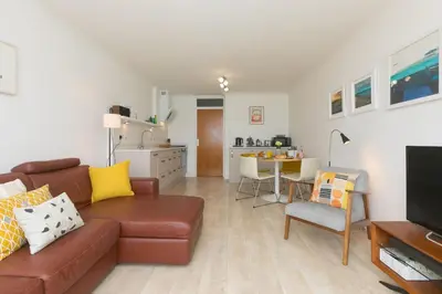 a living room with a brown couch and a kitchen at 28 Carrack Widden in St Ives