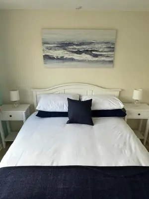 a bedroom with a white bed with two night stands at Stable Door Cottage in Newquay