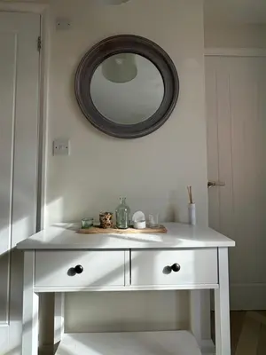 a white dressing table with a mirror on the wall at Stable Door Cottage in Newquay