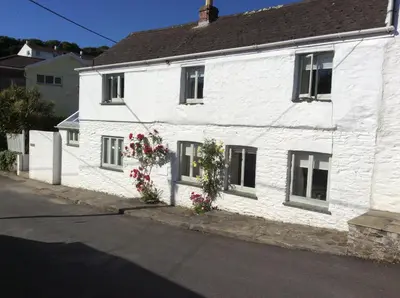 a white house with flowers on the side of it at Roses Cottage in Porthscatho
