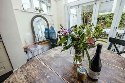 a bottle of wine and a vase of flowers on a table at Roses Cottage in Porthscatho