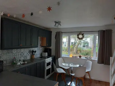 a kitchen with blue cabinets and a table and chairs at 78 Atlantic Reach in Newquay