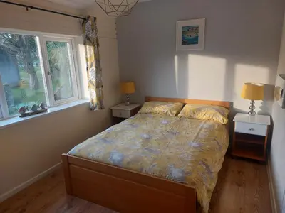 a bedroom with a bed with two night stands and two windows at 78 Atlantic Reach in Newquay
