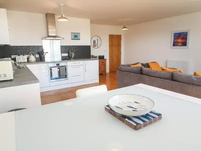 a kitchen and living room with a table in a kitchen at Newquay, Beach Charm and Town Vibes with Parking in Newquay