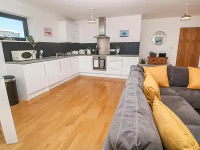 a living room with a couch and a kitchen at Newquay, Beach Charm and Town Vibes with Parking in Newquay