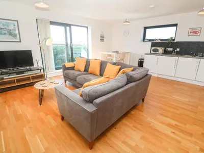 a living room with a gray couch and a television at Newquay, Beach Charm and Town Vibes with Parking in Newquay