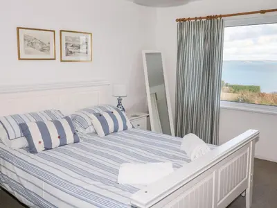 a bedroom with a bed with a view of the ocean at Waverley in St Austell