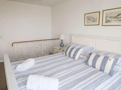 a bed with blue and white striped sheets and pillows at Waverley in St Austell