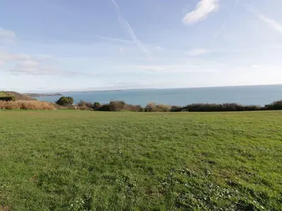 a field of green grass with the ocean in the background at Waverley in St Austell