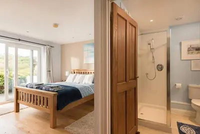 a bedroom with a bed and a bathroom with a shower at Cosy Beachfront Retreat with Stunning Sea Views & Free Access to a Local Indoor Pool in Talland