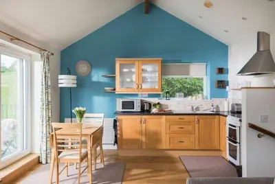 a kitchen with a table and a blue wall at Cosy Beachfront Retreat with Stunning Sea Views & Free Access to a Local Indoor Pool in Talland