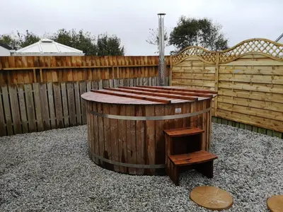 a hot tub in a backyard with a wooden fence at Cornish Coastal Bungalow in Padstow