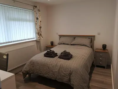 a bedroom with a bed with two bags on it at Cornish Coastal Bungalow in Padstow