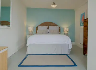 a bedroom with a white bed and two lamps at Mesmerising sea views - Penrose - above the beach Cornwall. in Downderry