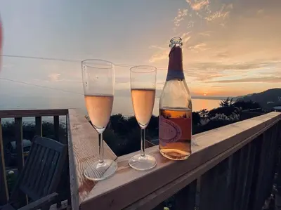two glasses of champagne and a bottle on a balcony at Mesmerising sea views - Penrose - above the beach Cornwall. in Downderry