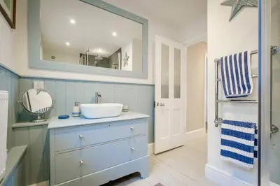 a bathroom with a sink and a mirror at Mesmerising sea views - Penrose - above the beach Cornwall. in Downderry