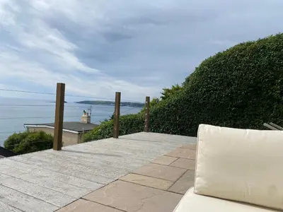 a laptop sitting on a patio overlooking the ocean at Mesmerising sea views - Penrose - above the beach Cornwall. in Downderry
