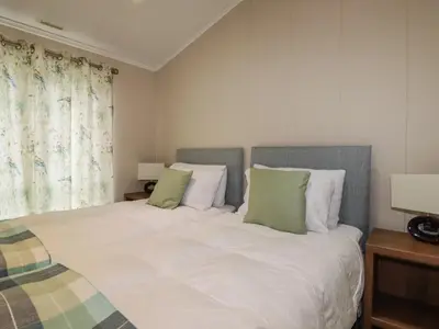 a bedroom with a bed with white sheets and green pillows at Haven Lodge in Tintagel
