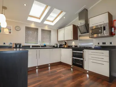 a large kitchen with white cabinets and a skylight at Haven Lodge in Tintagel