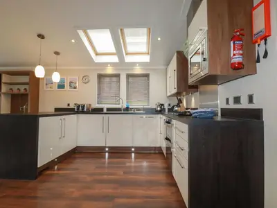 a large kitchen with white cabinets and a skylight at Haven Lodge in Tintagel